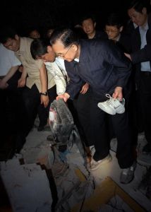2008年5月12日，温家宝总理在都江堰市聚源中学教学楼的废墟上捡起学生的鞋子和书包，心情沉重。