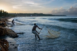 海地人将渔网收回海滩的情景